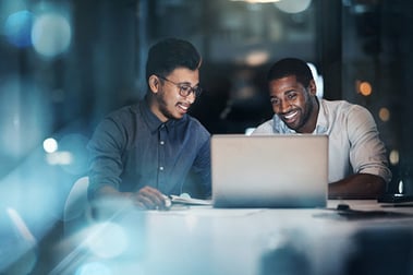 Zwei Männer sitzen vor Laptop und erstellen Präsentation mit KI