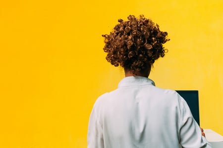 Frau am Laptop mit Rücken zum Betrachter symbolisiert Arbeit mit Webhosting